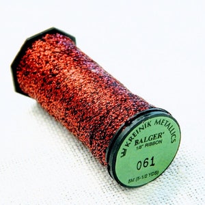 May include: A spool of 1/8 inch metallic ribbon in a copper color. The spool is labeled "Kreinik Metallics Balger 1/8" Ribbon 061 5M (5-1/2 YDS)"