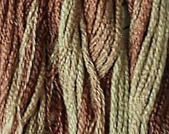 May include: Close-up of a bundle of embroidery floss in shades of brown and beige.