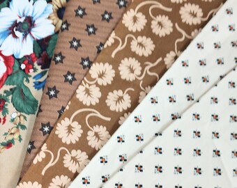 May include: Four fabric swatches with different patterns. The first swatch has a floral pattern with red, white, and green flowers on a beige background. The second swatch has a brown background with small white stars. The third swatch has a brown background with a pattern of light brown flowers. The fourth swatch has a white background with a small, repeating pattern of black and orange squares.
