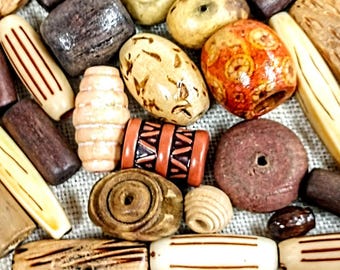 May include: A collection of wooden beads in various shapes, sizes, and colors. The beads are made of natural wood and have a rustic, handcrafted look. Some beads have intricate patterns and designs.
