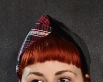 May include: A woman with red hair is wearing a black and red plaid hat with a black velvet band. The hat is angled on her head and she is looking to the side.