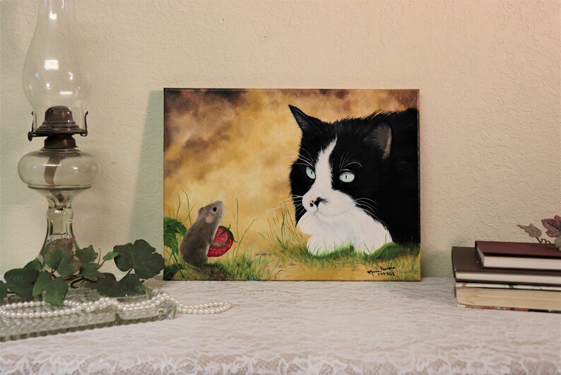 Puede incluir: Una pintura de un gato blanco y negro con ojos verdes mirando a un peque&ntilde;o rat&oacute;n marr&oacute;n que sostiene una fresa roja. El fondo es de color amarillo-marr&oacute;n con hierba verde.