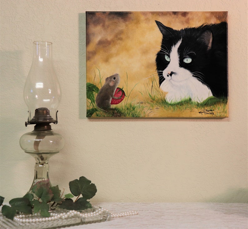 Puede incluir: Una pintura de un gato blanco y negro con ojos verdes mirando a un peque&ntilde;o rat&oacute;n marr&oacute;n que sostiene una fresa roja. El fondo es un paisaje amarillo y marr&oacute;n.