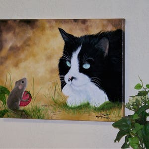 Puede incluir: Un gato blanco y negro con ojos verdes mira fijamente a un peque&ntilde;o rat&oacute;n marr&oacute;n que sostiene una fresa roja. La pintura est&aacute; sobre un fondo marr&oacute;n y verde.