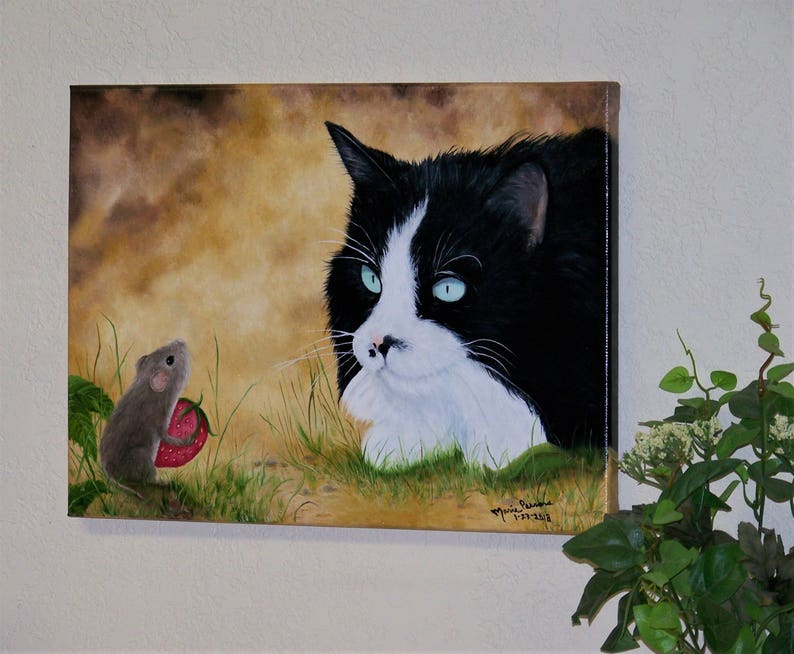 Puede incluir: Un gato blanco y negro con ojos verdes mira fijamente a un peque&ntilde;o rat&oacute;n marr&oacute;n que sostiene una fresa roja. La pintura est&aacute; sobre un fondo marr&oacute;n y verde.