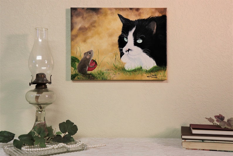 Puede incluir: Una pintura de un gato blanco y negro con ojos verdes mirando a un peque&ntilde;o rat&oacute;n marr&oacute;n que sostiene una fresa roja. El fondo es un paisaje amarillo y marr&oacute;n.
