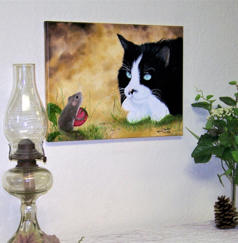 Puede incluir: Una pintura de un gato blanco y negro mirando a un peque&ntilde;o rat&oacute;n gris que sostiene una fresa roja. El gato est&aacute; acostado y el rat&oacute;n est&aacute; de pie sobre sus patas traseras. El fondo es un paisaje marr&oacute;n y verde.