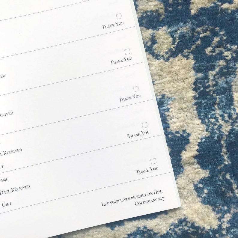 May include: A white gratitude journal with a blue and white patterned background. The journal has a section for listing gifts received, with checkboxes for marking gifts as acknowledged. The journal also includes the quote "Let your lives be built on Him. Colossians 2:7".