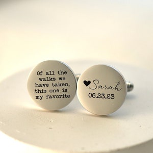 May include: A pair of silver cufflinks with engraved text. One cufflink reads "Of all the walks we have taken, this one is my favourite". The other cufflink reads "Sarah 06.23.23".