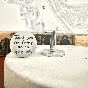 May include: Silver cufflinks with a round engraved message that reads "Thank you for loving me as your own".