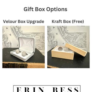 May include: Two gift box options for cufflinks. A white velour box with a pair of silver cufflinks and a brown kraft box with a pair of silver cufflinks. The text "Gift Box Options" is at the top of the image. The text "Velour Box Upgrade" is above the white box. The text "Kraft Box (Free)" is above the brown box. The text "ERIN BESS" is at the bottom of the image.