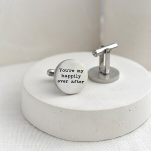 May include: Silver cufflinks with a round, engraved design. The engraving reads "You're my happily ever after".