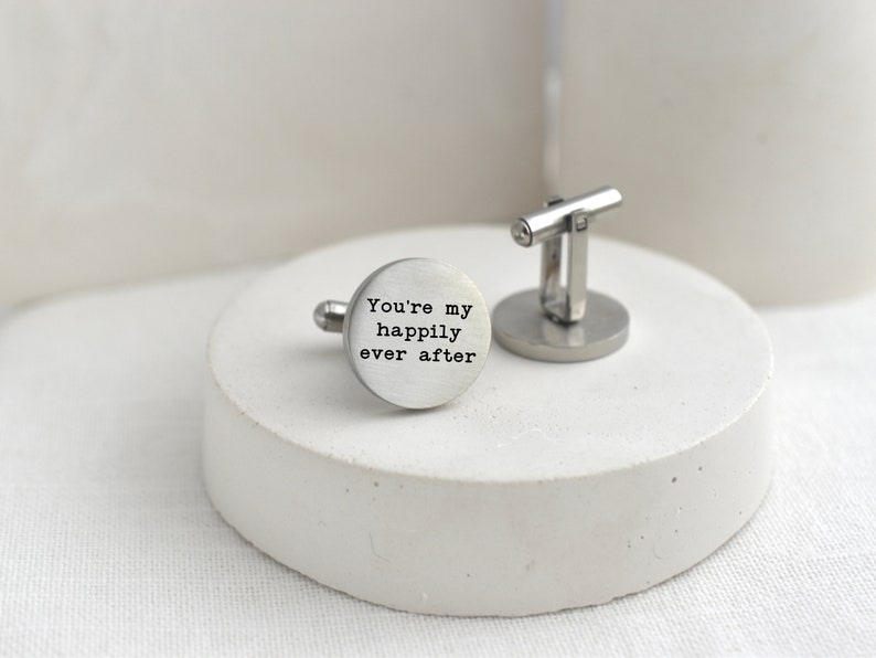 May include: Silver cufflinks with a round, engraved design. The engraving reads "You're my happily ever after".
