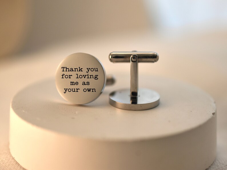 May include: Silver cufflinks with a round, engraved message that reads "Thank you for loving me as your own".