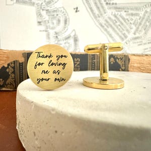 May include: Gold cufflinks with a round engraved message that reads "Thank you for loving me as your own".