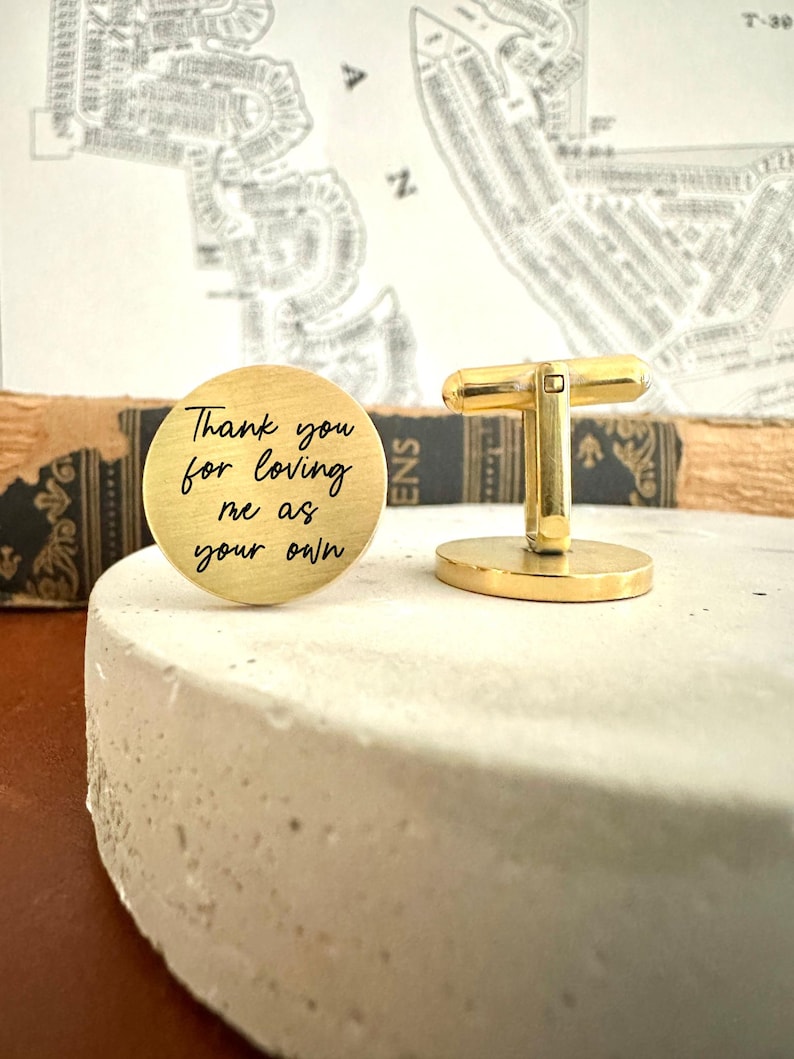 May include: Gold cufflinks with a round engraved message that reads "Thank you for loving me as your own".