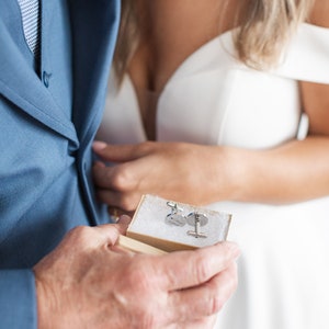 May include: A close-up of a small, rectangular box with two silver cufflinks inside. The cufflinks are round and have a design on them. The box is open and the cufflinks are visible.