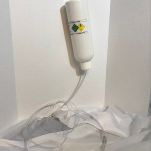 May include: A white cylinder with a blue and green label hanging from a hook. The cylinder is connected to a clear plastic tube.