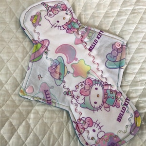 Protector de bragas de tela reutilizable con estampado de gatito de 10,25" sobre algodón (Cordón Windpro regular con broche en forma de corazón)