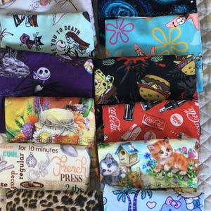 Puede incluir: Una colección de bolsas de tela con varios diseños. Los diseños incluyen espacio, personajes de dibujos animados, comida, estampados florales y de animales. Algunas bolsas tienen texto, como "French Press" y "You to Death."