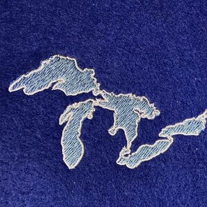 May include: A white outline of the Great Lakes on a dark blue background.