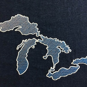 May include: A white outline of the Great Lakes on a dark blue background. The lakes are filled in with a light blue color.