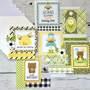 May include: A collection of handmade greeting cards with bee and bear-themed designs. The cards feature yellow, black, and white patterns, with phrases like "Sweet as honey" and "Happy Birthday." Includes blank white cards and decorative elements.