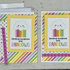 May include: Two handmade greeting cards with a yellow, white, and rainbow cloud design. The cards feature the text "Sending sunshine and rainbows".