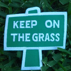 May include: Green and white embroidered patch with the text "Keep on the grass".