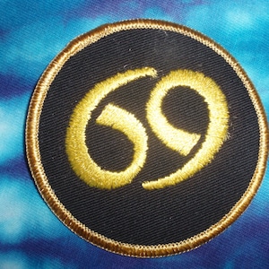 May include: A round black patch with a gold embroidered number 69 in the center.