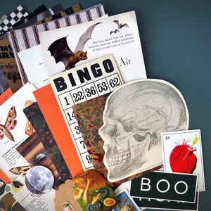May include: A selection of vintage ephemera with a Halloween theme. Includes a bingo card, a skull diagram, a bat illustration, and a card that says "BOO". The colour palette is a mix of orange, black, white, and brown.