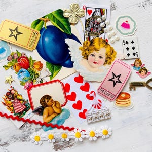 May include: A collection of vintage ephemera including a heart-shaped card with red hearts, a ticket with the number 9410973, a ticket with the number 0602395, a card with a cherub, a card with a queen of hearts, a card with a pancake, a card with a flower bouquet, a card with a plum, a card with a key, a card with a cupcake, and a card with a small cake.
