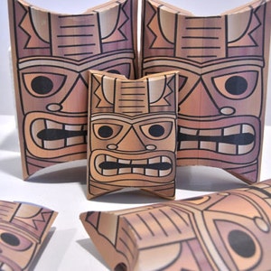 May include: Five brown cardboard boxes with a tiki face design. The boxes are shaped like pillows and have a brown, black, and white color scheme.