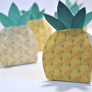 May include: Four yellow pineapple-shaped boxes with green leaves. The boxes are made of paper and have a pineapple pattern.