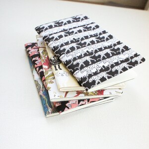 Puede incluir: Una pila de cinco cuadernos con cubiertas estampadas. El cuaderno superior tiene un estampado de guepardo en blanco y negro. Otras cubiertas presentan dise&ntilde;os florales e ilustrados en rosa, verde y azul. Los cuadernos tienen p&aacute;ginas blancas.