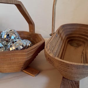 May include: Two wooden baskets with handles. One basket is filled with silver disco balls. Both baskets have a natural wood finish and stand on small wooden feet.