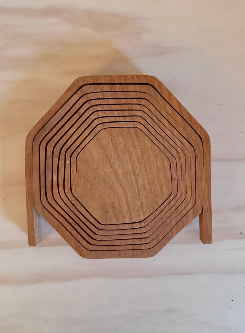 May include: A set of eight wooden octagonal nesting trays. The trays are made of light brown wood and are stacked on top of each other.