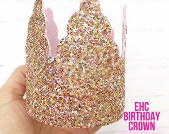 Könnte beinhalten: Eine rosa und goldene Glitzer-Geburtstagskrone mit einem gewellten Rand. Die Krone ist aus Filz und hat ein rosafarbenes Innenleben. Der Text "EHC BIRTHDAY CROWN SVG FILE" ist auf einem weißen Hintergrund unter der Krone gedruckt.