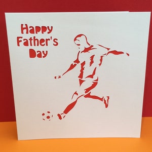 May include: A white card with red text that says "Happy Father's Day". A red silhouette of a soccer player kicking a ball is on the card.