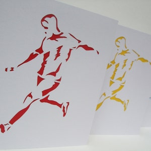 May include: Three paper cutouts of a soccer player kicking a ball. The player on the left is red, the middle player is yellow, and the player on the right is blue.