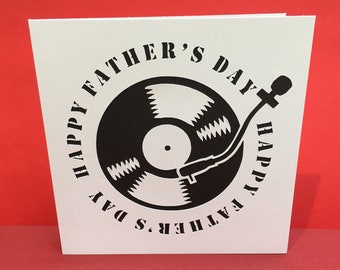 May include: White card with black text that reads "Happy Father's Day" in a circle around a black and white illustration of a record player.