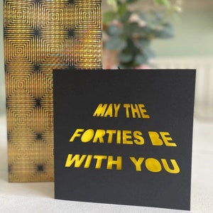 May include: A black card with gold lettering that reads "May the Forties Be With You".