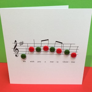 May include: A white card with a musical staff and notes. Red and green buttons are placed on the notes to spell out "We wish you a merry Christmas".