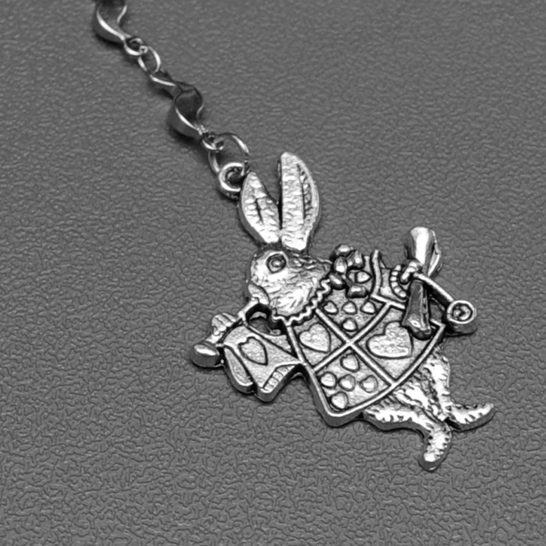 Alice in Wonderland tea party themed metal bookmark with a white rabbit charm showing detail