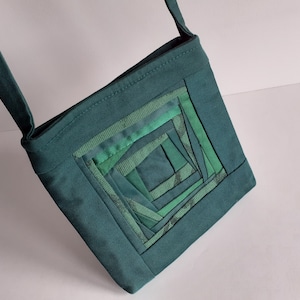 Può includere: Una borsa a tracolla in tessuto verde acqua con un design a patchwork quadrato in tonalità di verde.