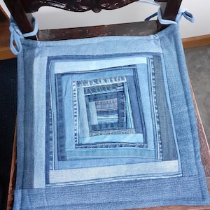 May include: A blue denim chair cushion with a square pattern made from different shades of blue denim.