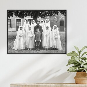 K&ouml;nnte beinhalten: Ein Schwarzwei&szlig;foto einer Gruppe von Kindern, die in wei&szlig;e Roben und Schleier gekleidet sind und vor einem Geb&auml;ude stehen. Ein Mann in einem dunklen Anzug und Hut steht in der Mitte der Gruppe.