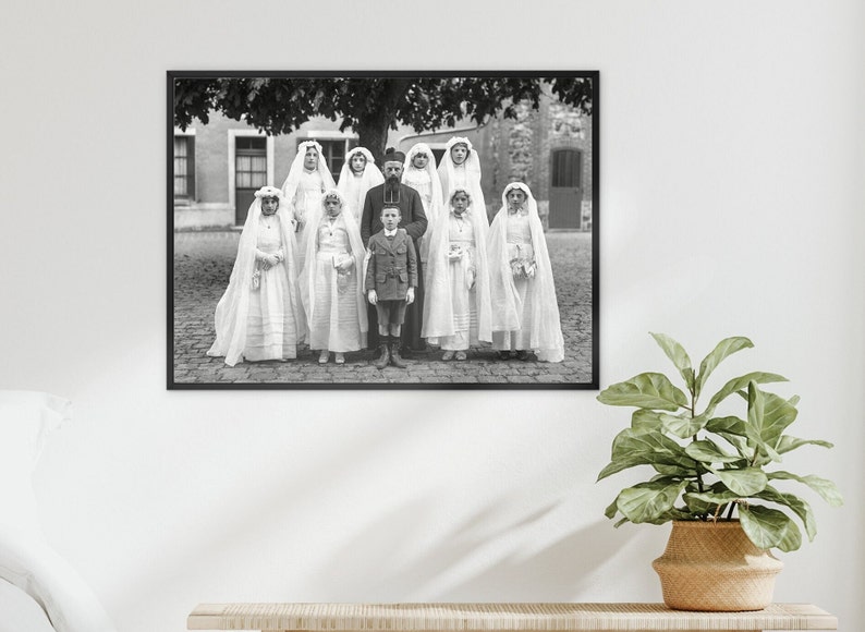 K&ouml;nnte beinhalten: Ein Schwarzwei&szlig;foto einer Gruppe von Kindern, die in wei&szlig;e Roben und Schleier gekleidet sind und vor einem Geb&auml;ude stehen. Ein Mann in einem dunklen Anzug und Hut steht in der Mitte der Gruppe.