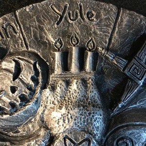 May include: A silver metal Yule incense burner with a five-pointed star design and the word "Yule" inscribed on the top.