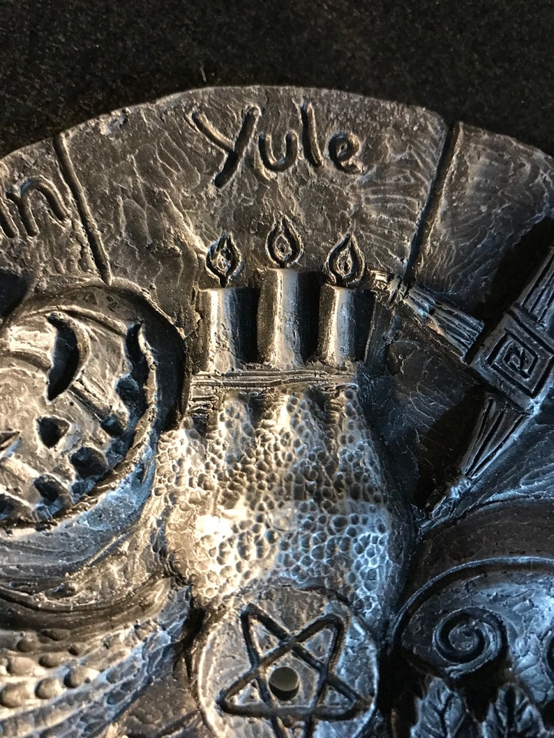 May include: A silver metal Yule incense burner with a five-pointed star design and the word "Yule" inscribed on the top.